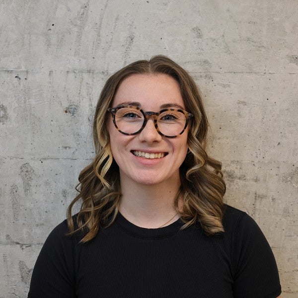 Rachael Belshaw photograph. Shows a smiling student with glasses and medium length, curly brown hair.